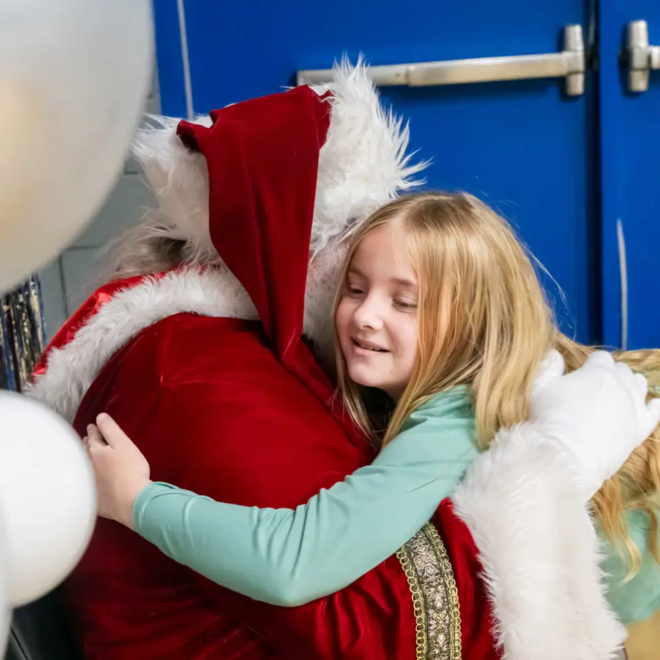 A girl beaming as she hugs Santa