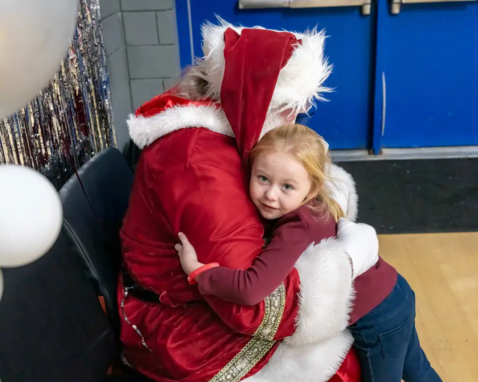 A little girl hugging Santa tight