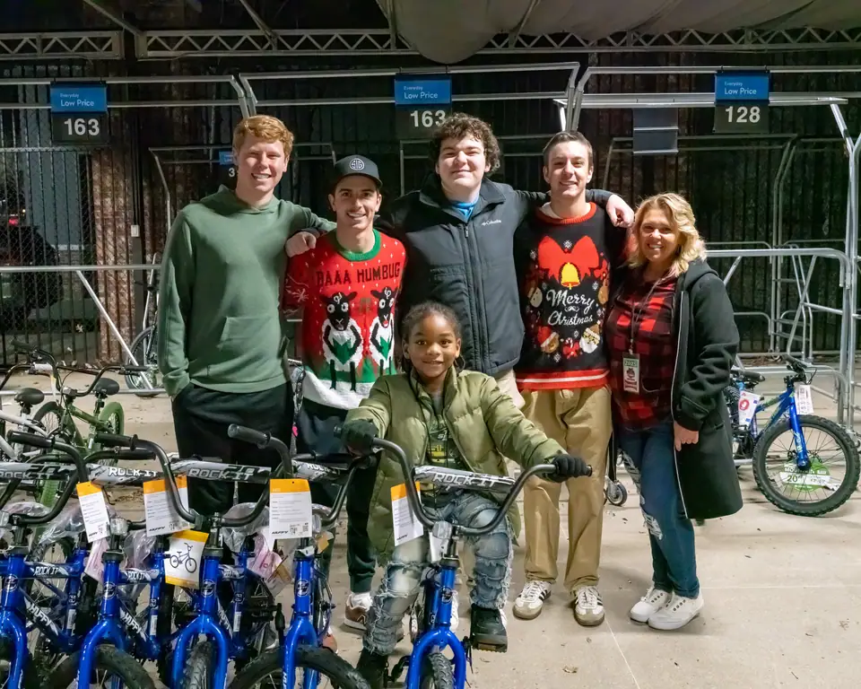 Chaperones and volunteers celebrating with a boy and his new bike