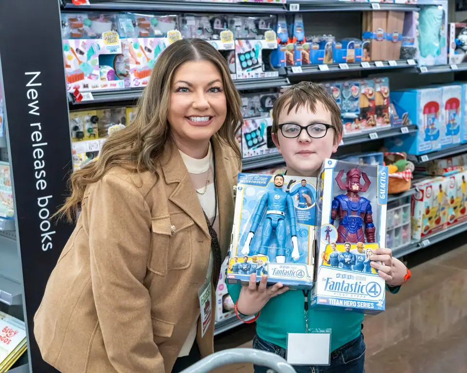 A boy proudly holding up the toys he picked out